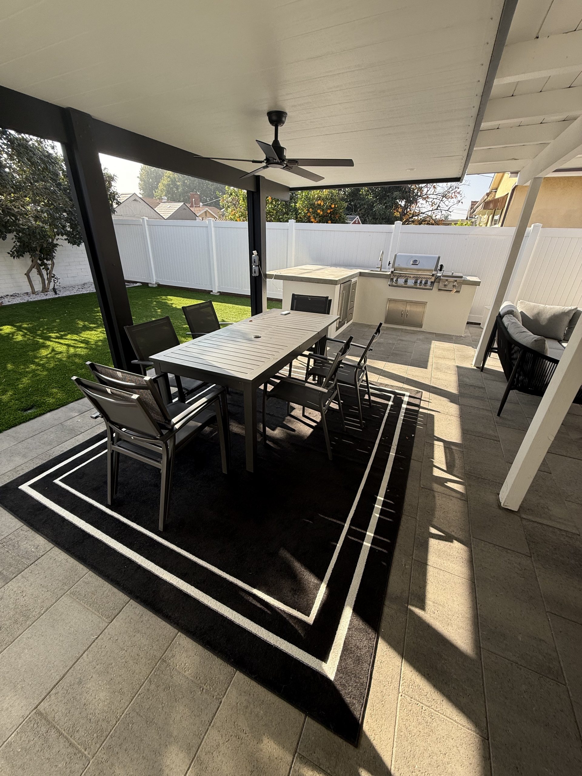 Covered patio with dining set, outdoor kitchen and turf lawn