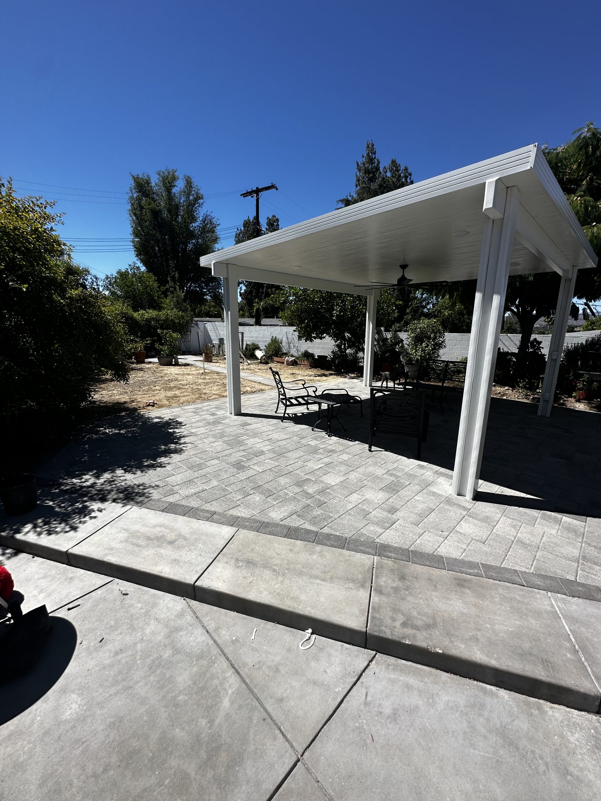 Freestanding white patio cover over a paver patio