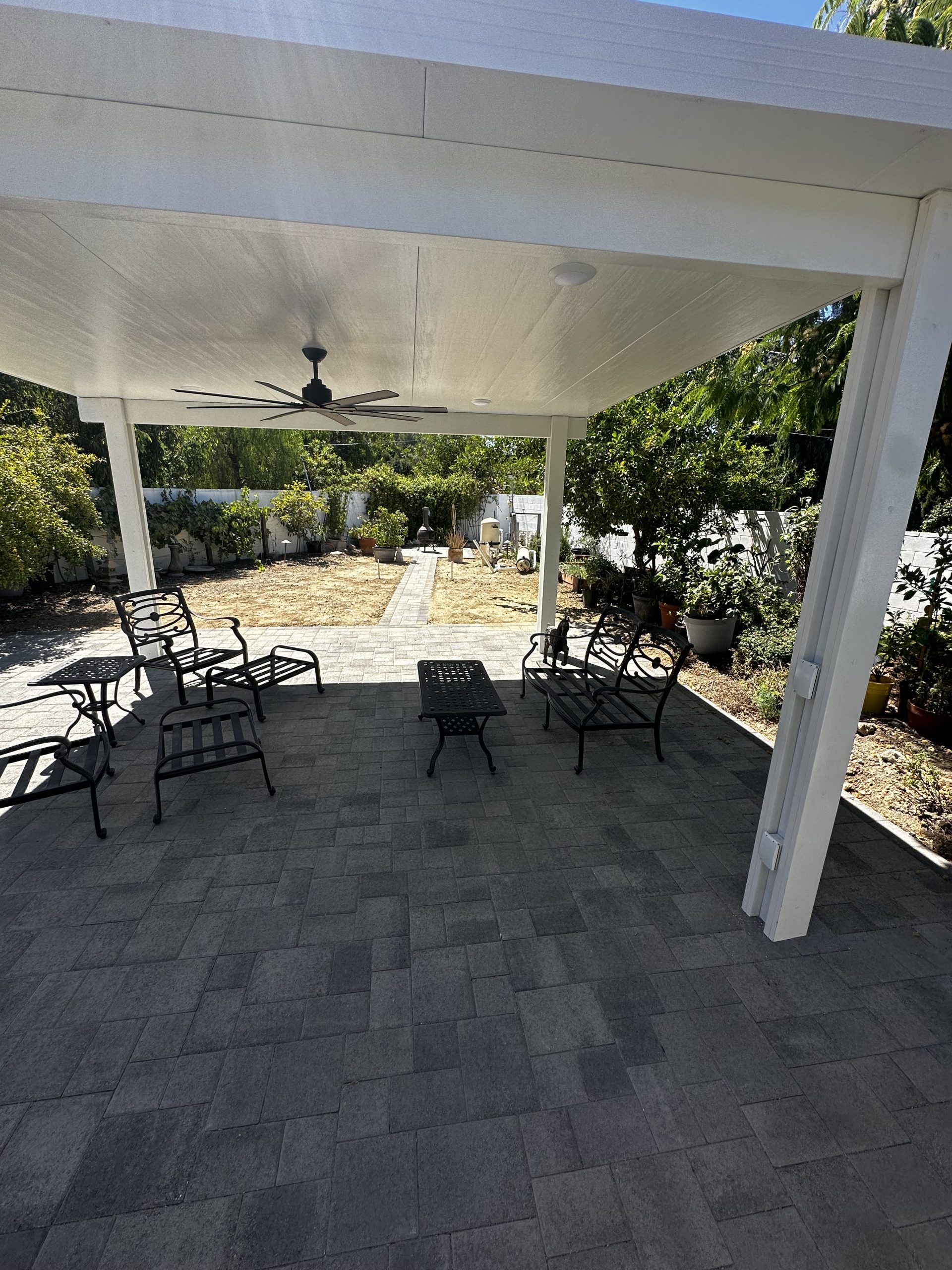White patio cover with ceiling fan and lounge seating