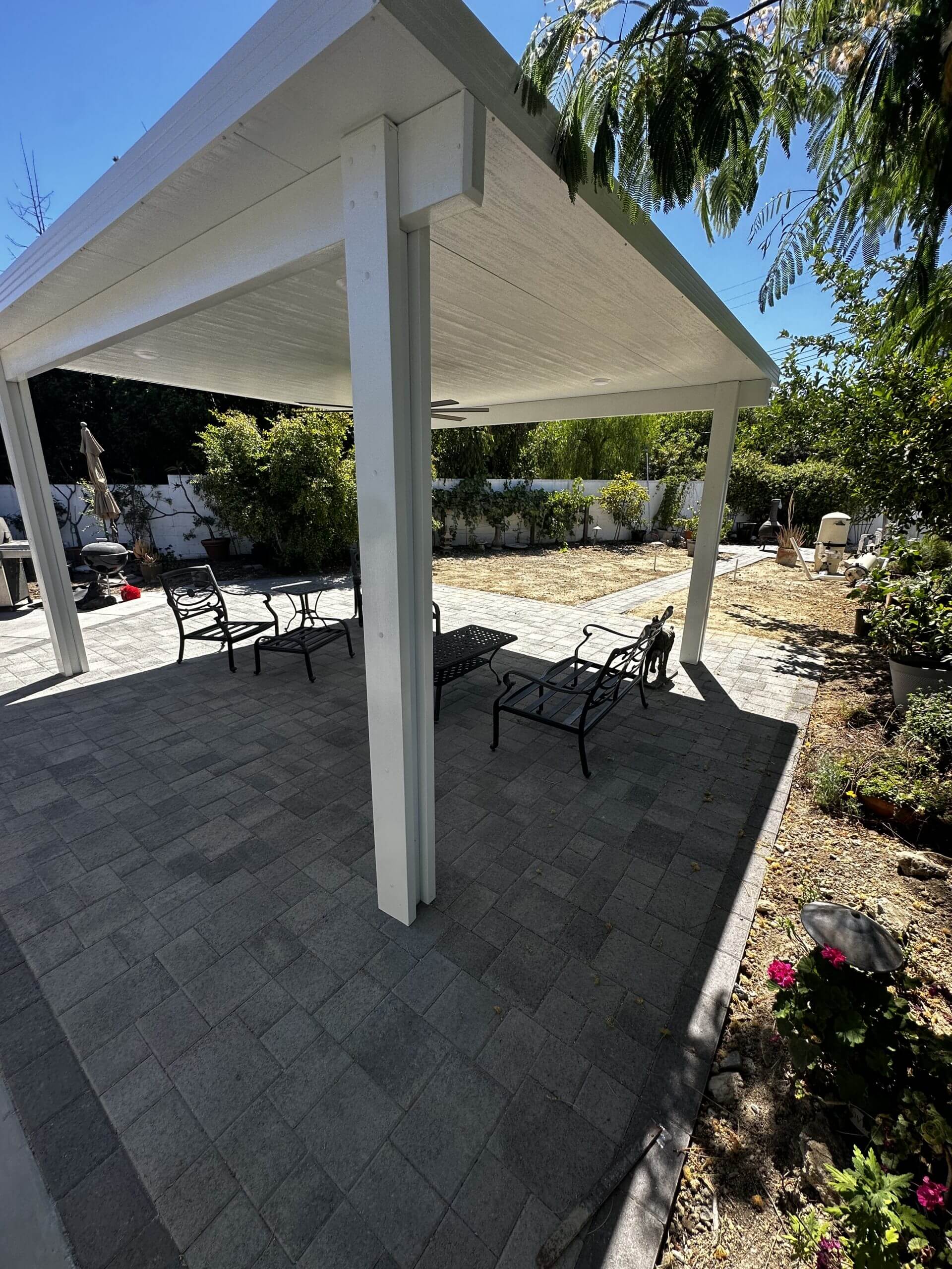 White gable patio cover with seating and garden