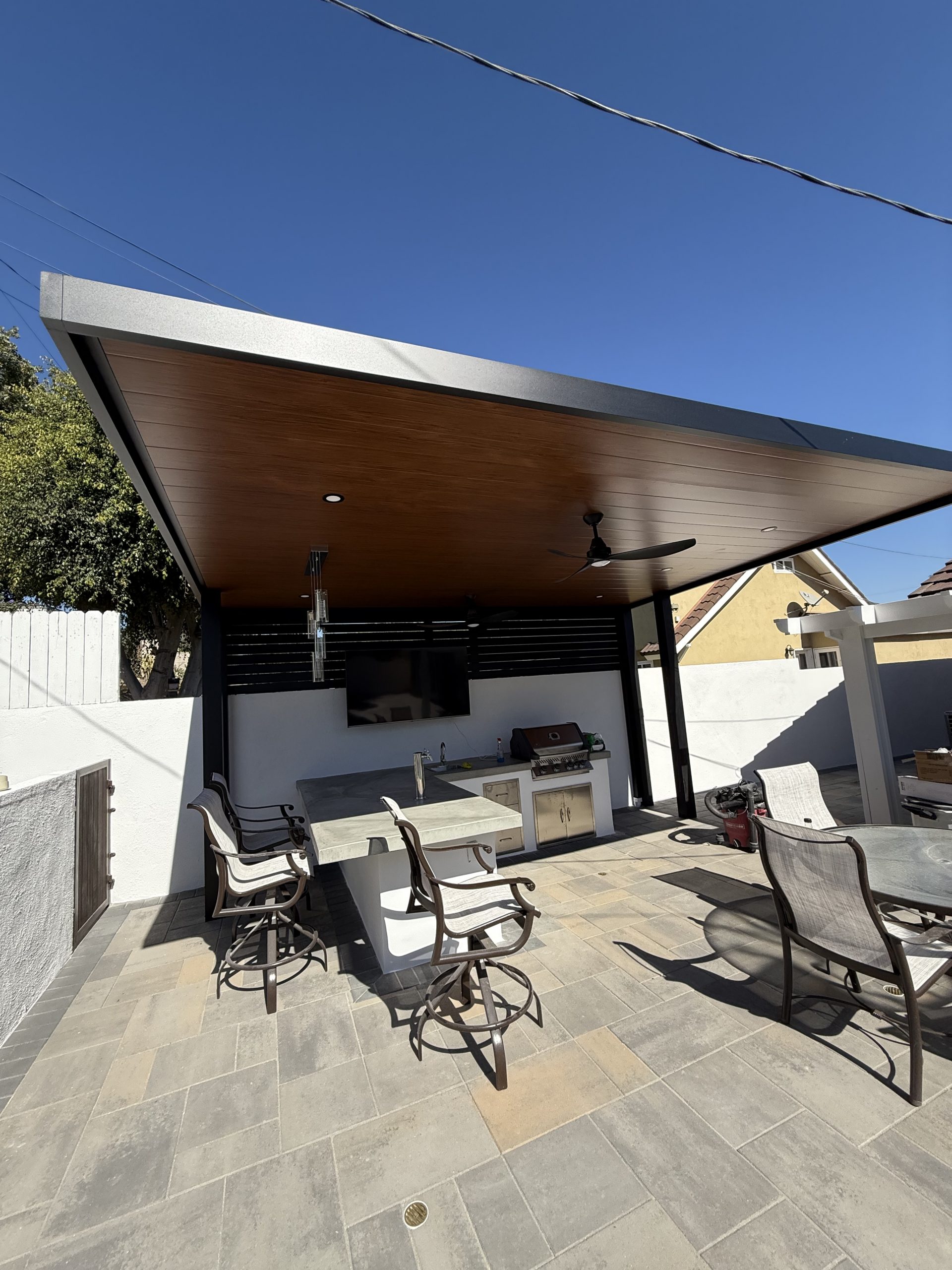 Modern cantilevered wood-ceiling patio cover with outdoor kitchen