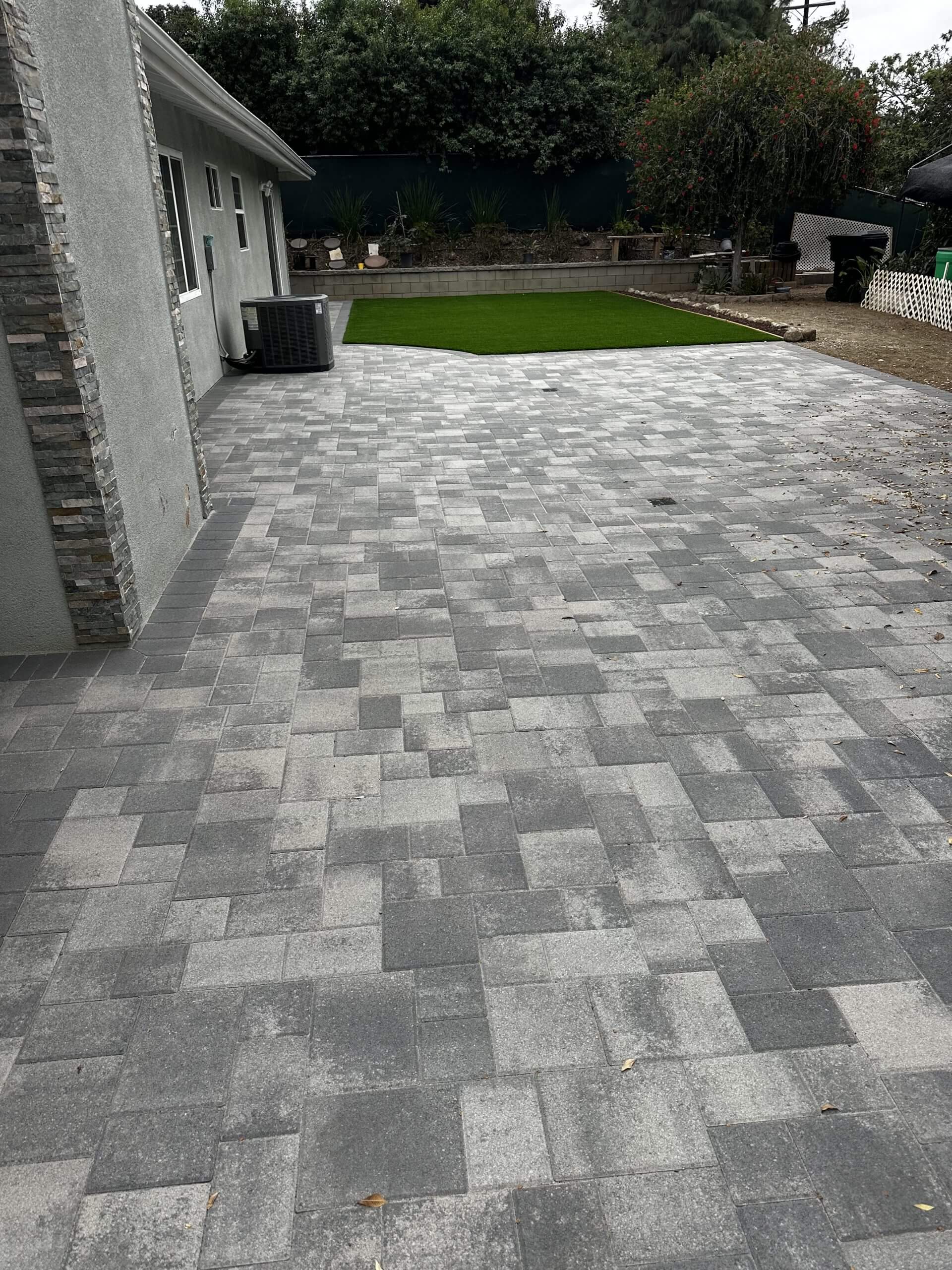 Modern paver patio with turf lawn and stone-veneer wall