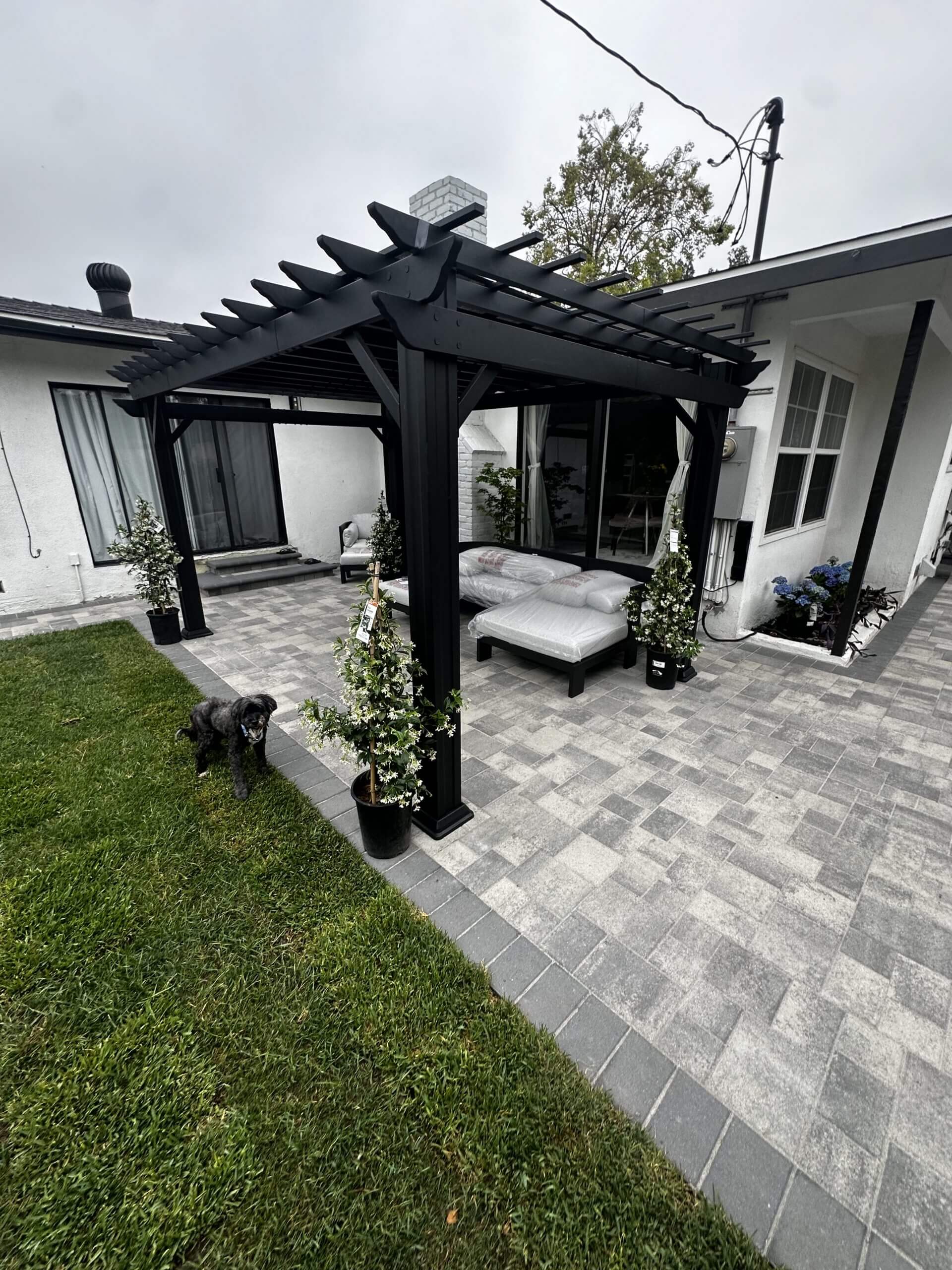 Pergola-covered paver patio with lounge seating and lawn
