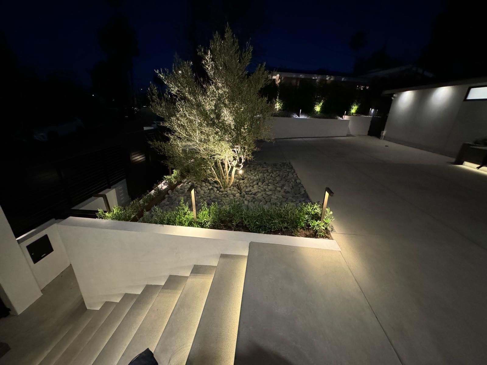 Concrete steps and driveway with landscape lighting at dusk