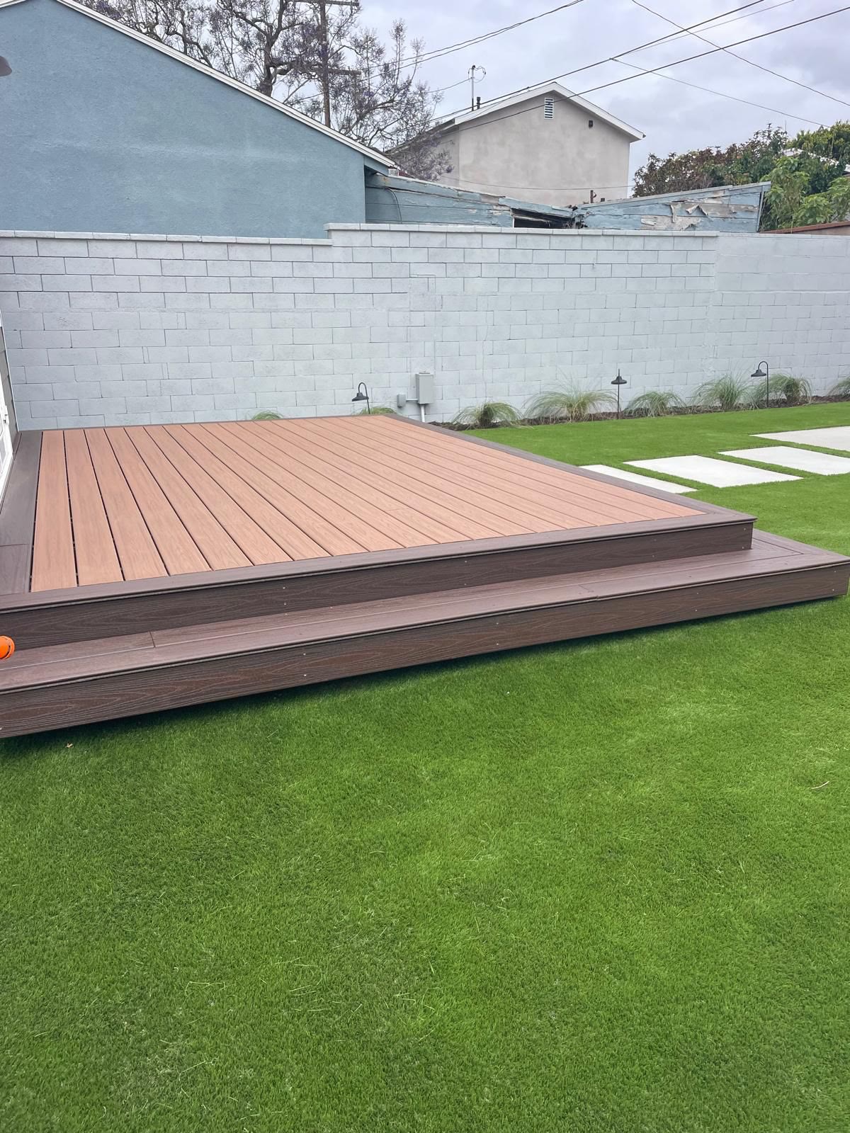Low-profile composite deck on a turf lawn behind a block wall