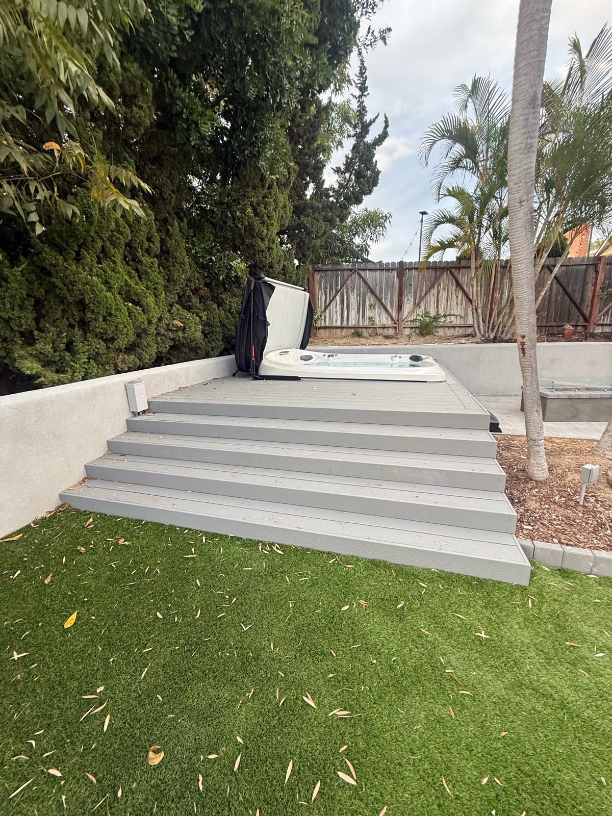 Gray composite deck steps leading up to a backyard spa