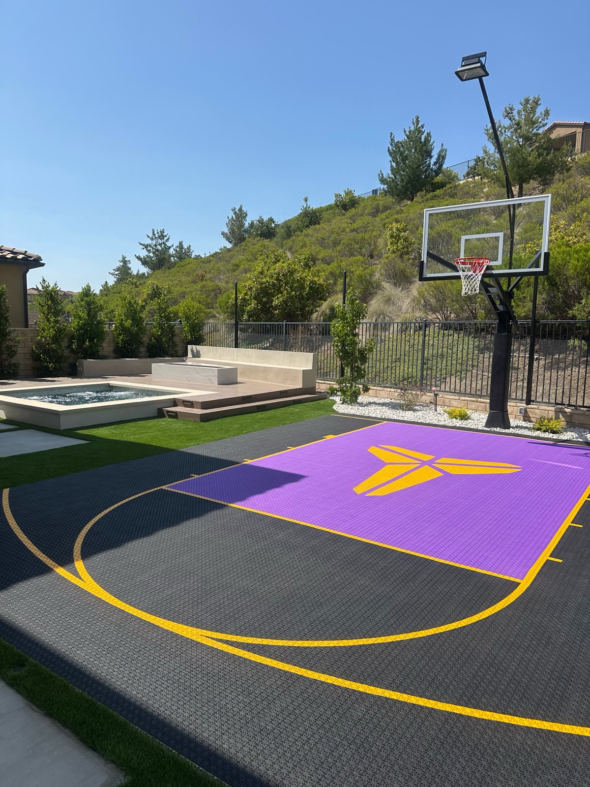 Purple-and-black sport court with Kobe logo, spa, and hillside backdrop