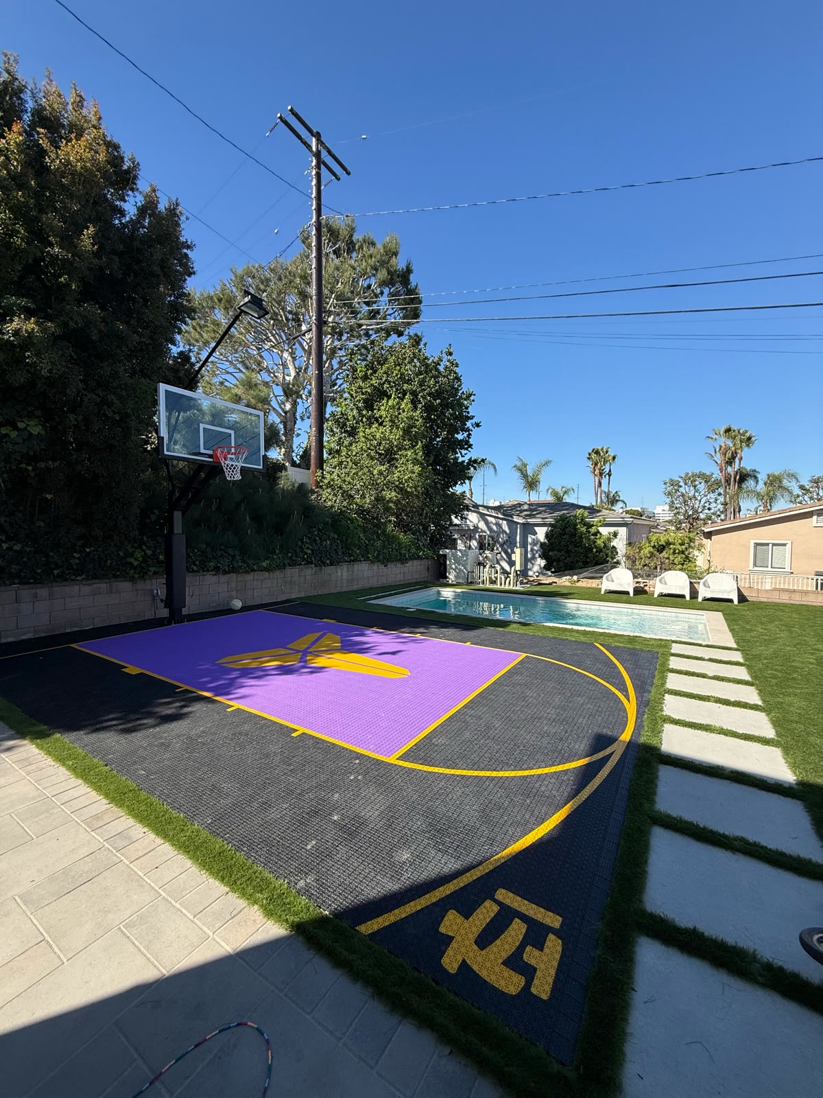 Purple Kobe sport court beside a pool with palm trees