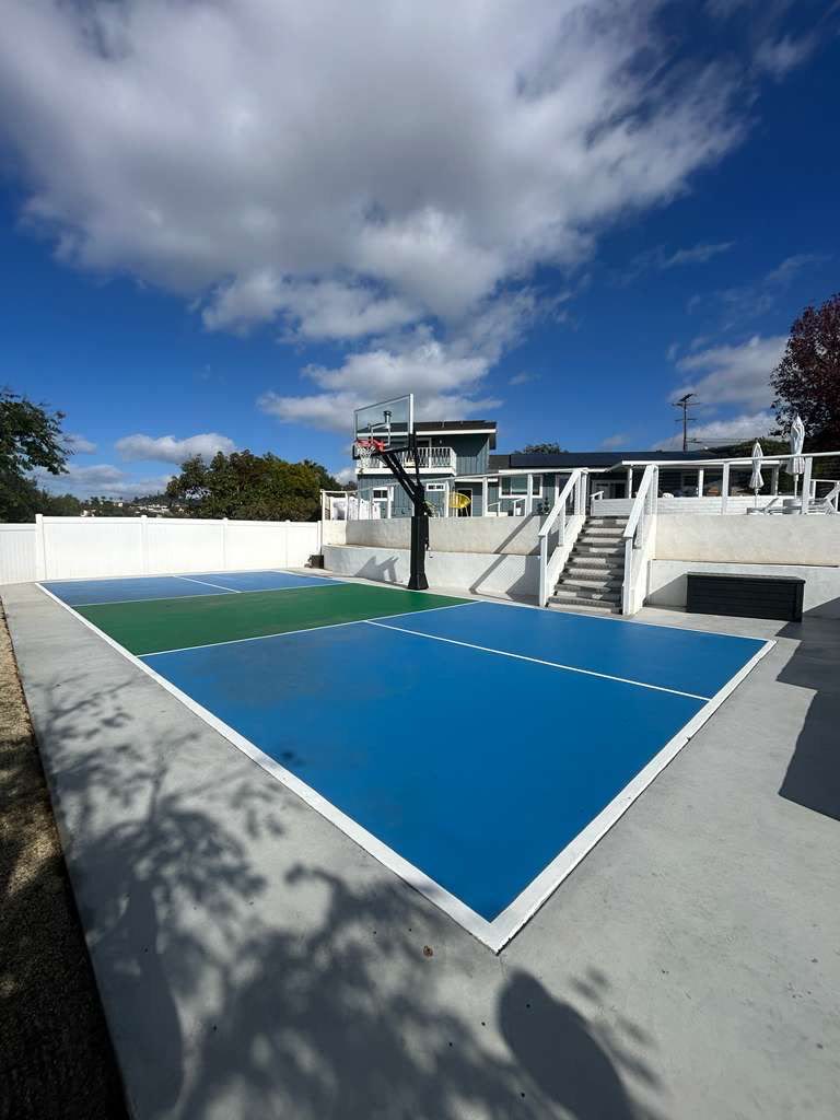 Blue-and-green multi-sport court with house and hillside view