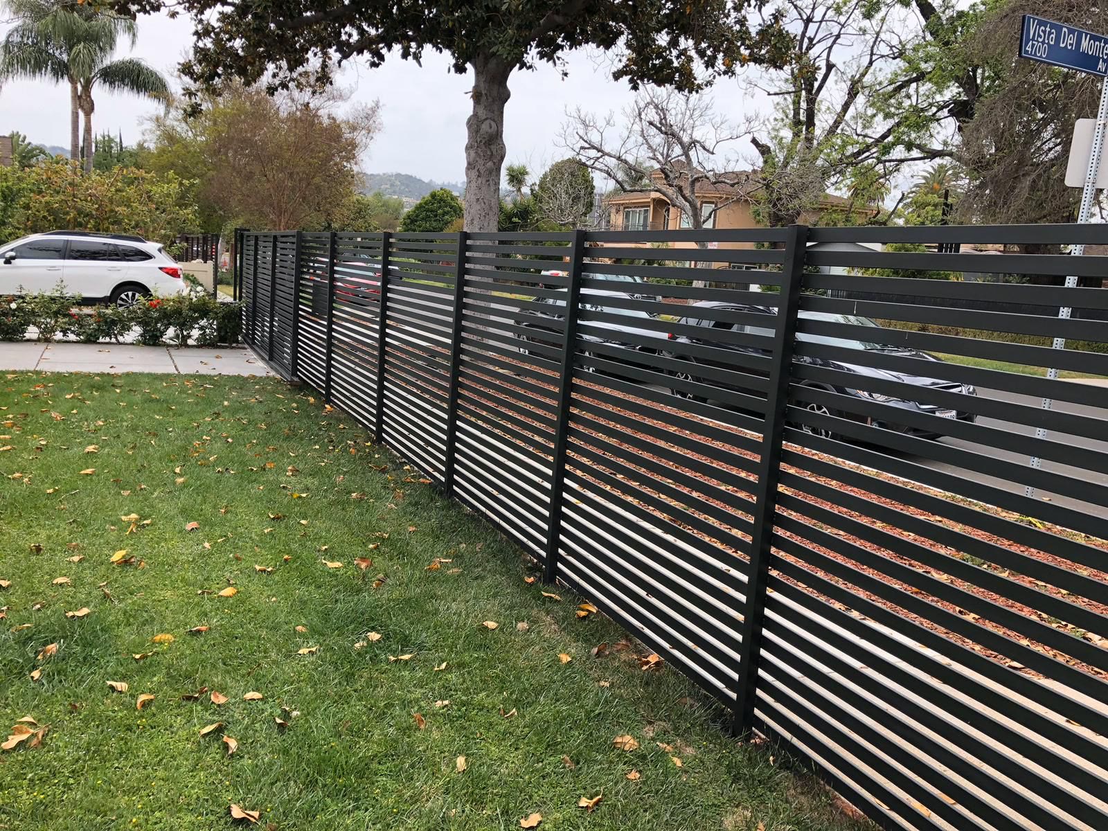 Black horizontal-slat fence lining a corner lawn