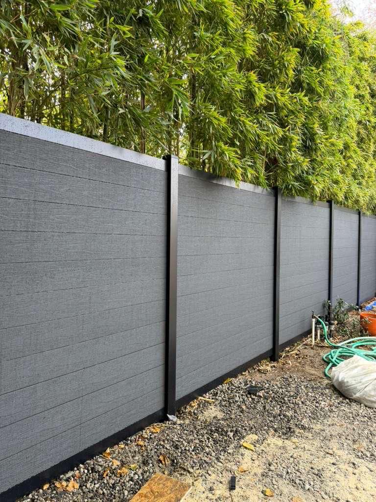 Gray composite privacy fence with bamboo backdrop