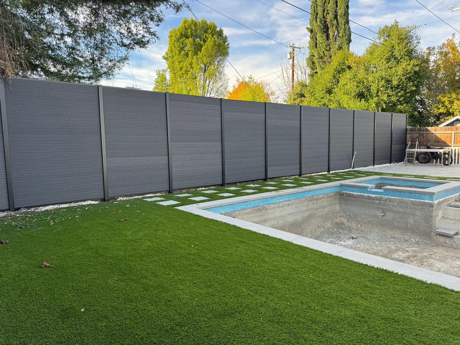 Gray composite privacy fence beside a new pool