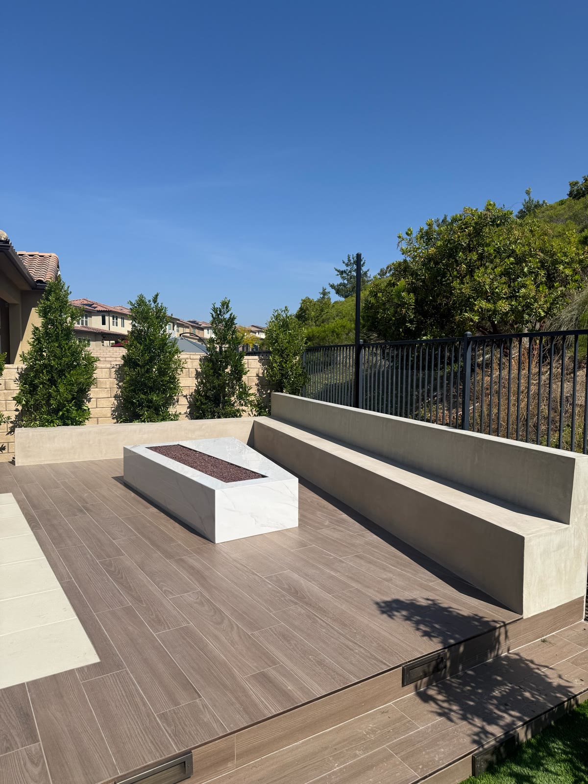 Minimalist linear fire pit with built-in bench on a wood-look deck