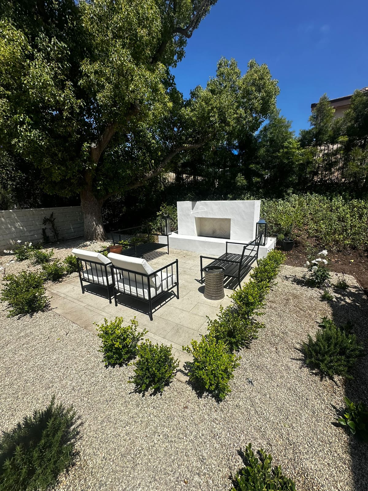 White stucco outdoor fireplace with seating in a garden