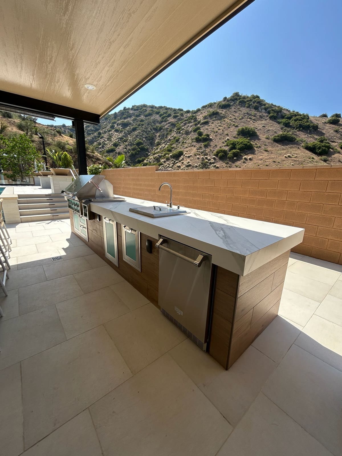 Sleek white-marble kitchen island with grill and hillside view
