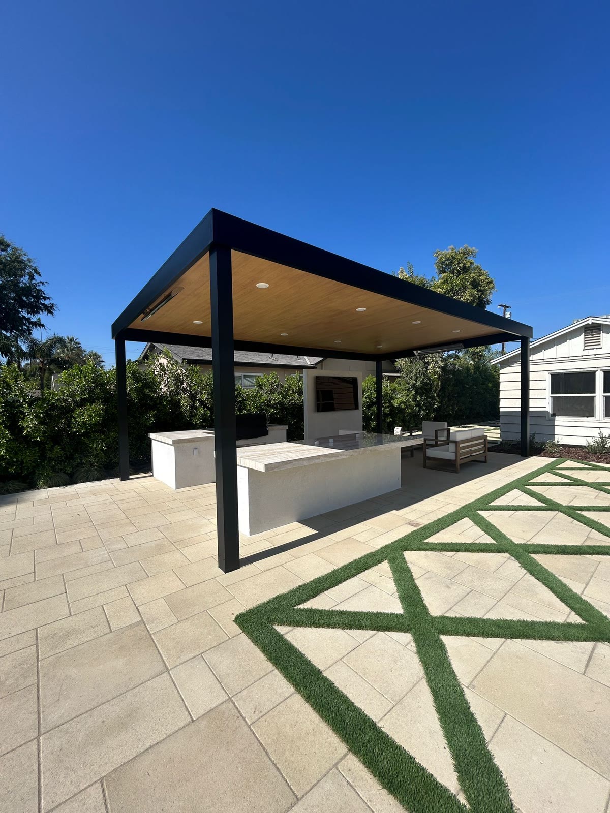 Modern pergola-covered outdoor kitchen over paver patio