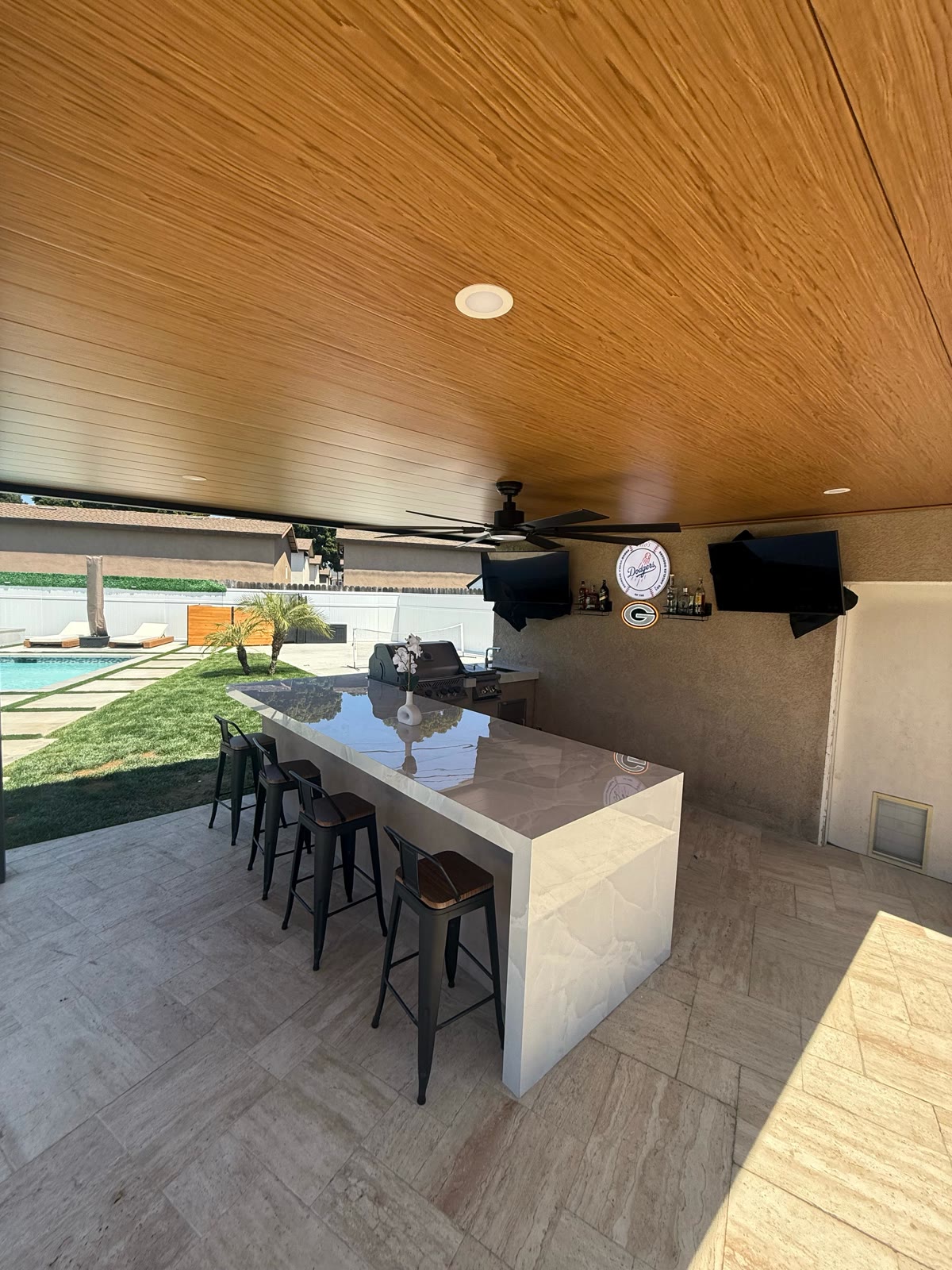 Bar-height marble island with stools under a wood-clad ceiling