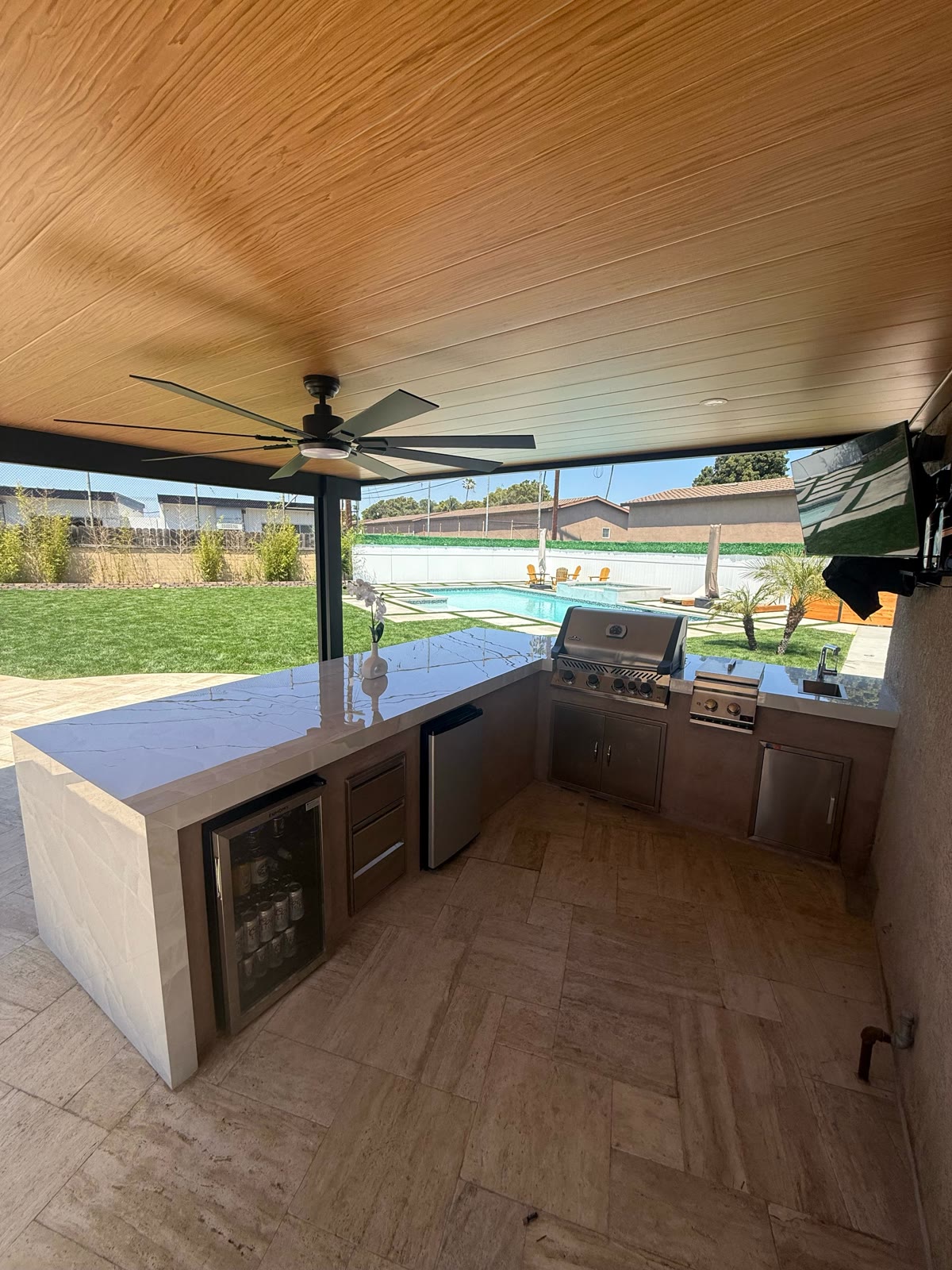 Solid wood-ceiling patio cover with ceiling fan, outdoor kitchen and pool view