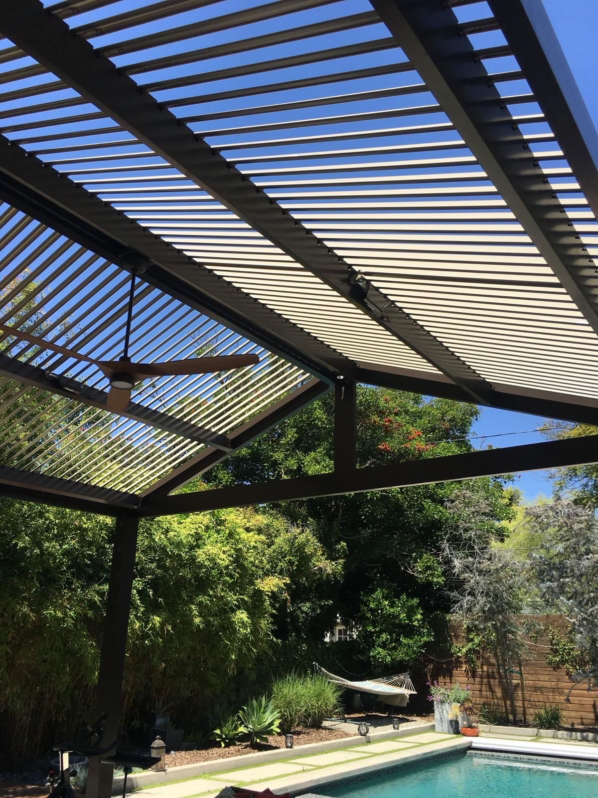 Louvered patio cover with ceiling fan above a pool