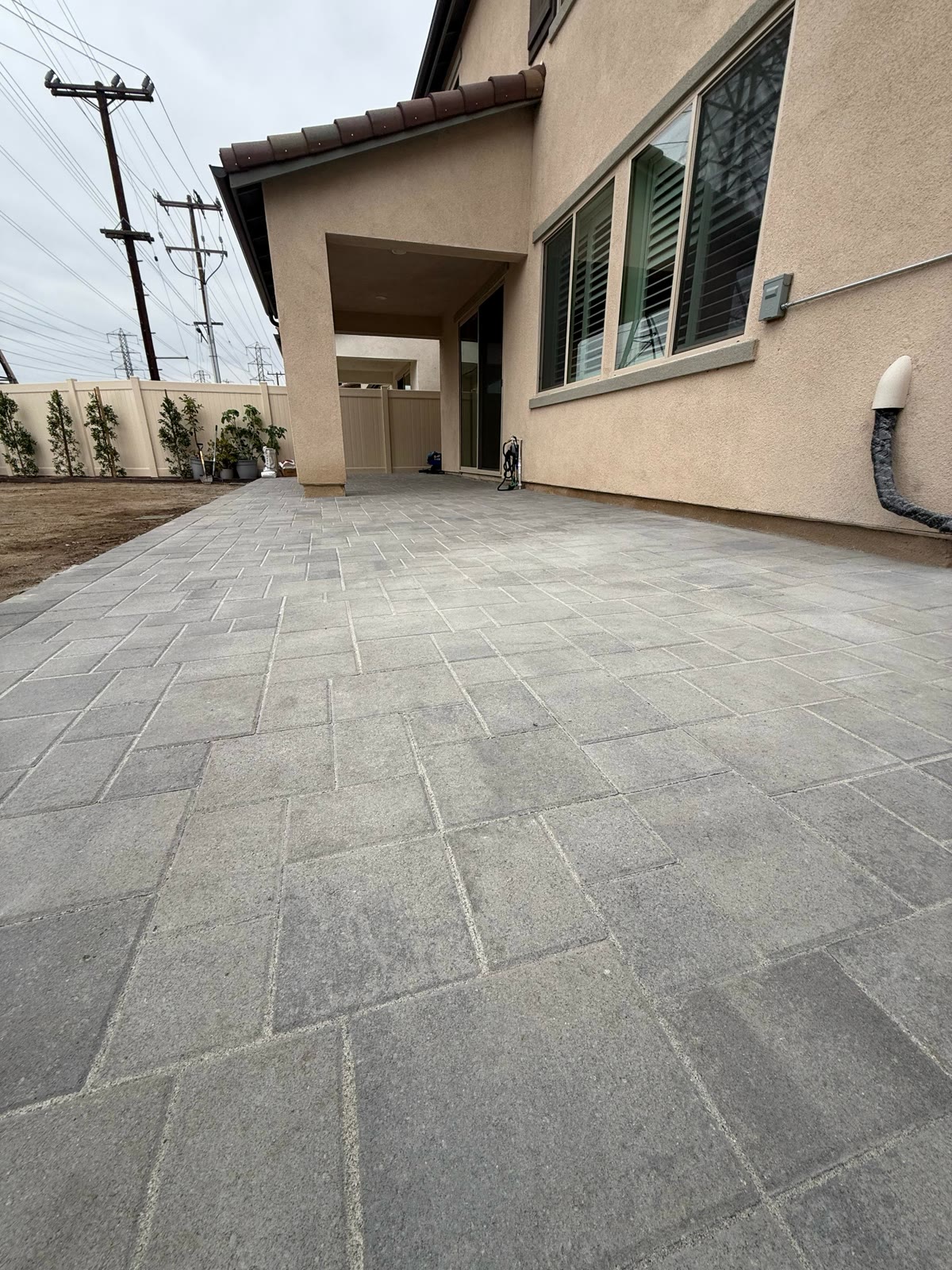 Gray paver patio beside a covered entry