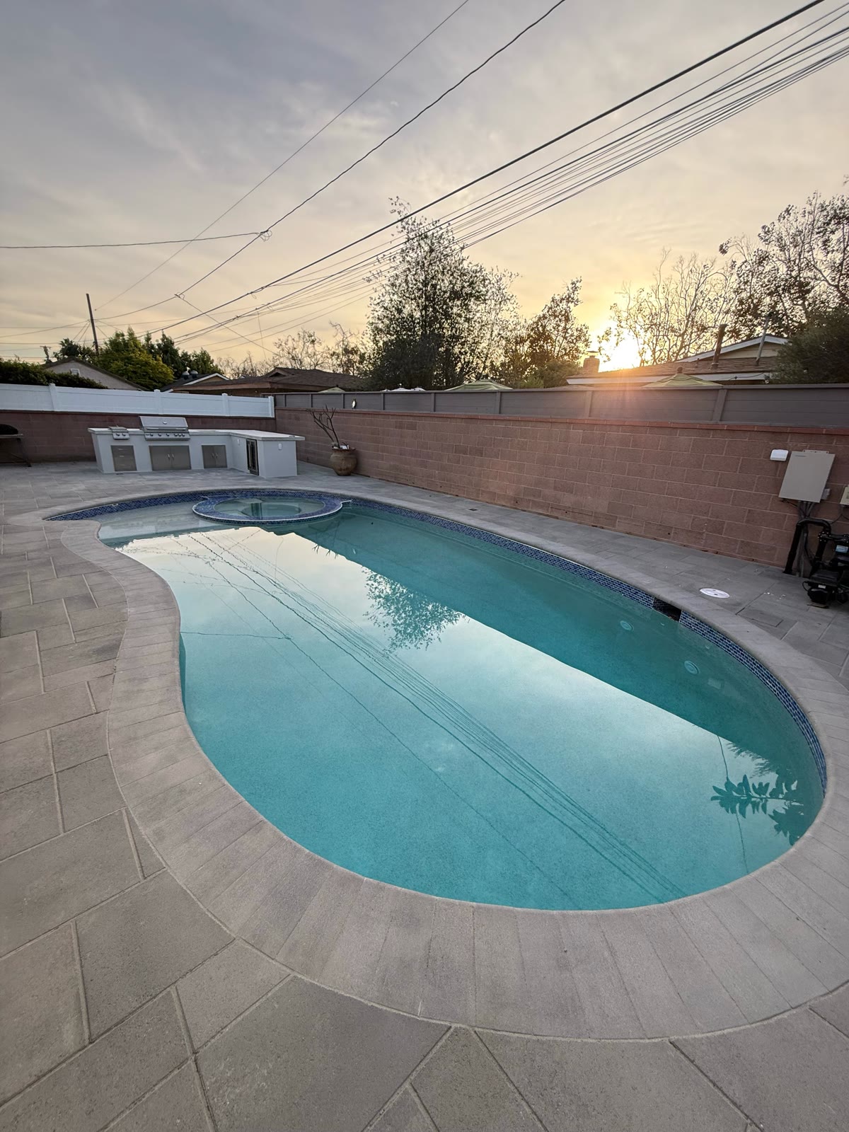 Freeform pool with outdoor kitchen at sunset