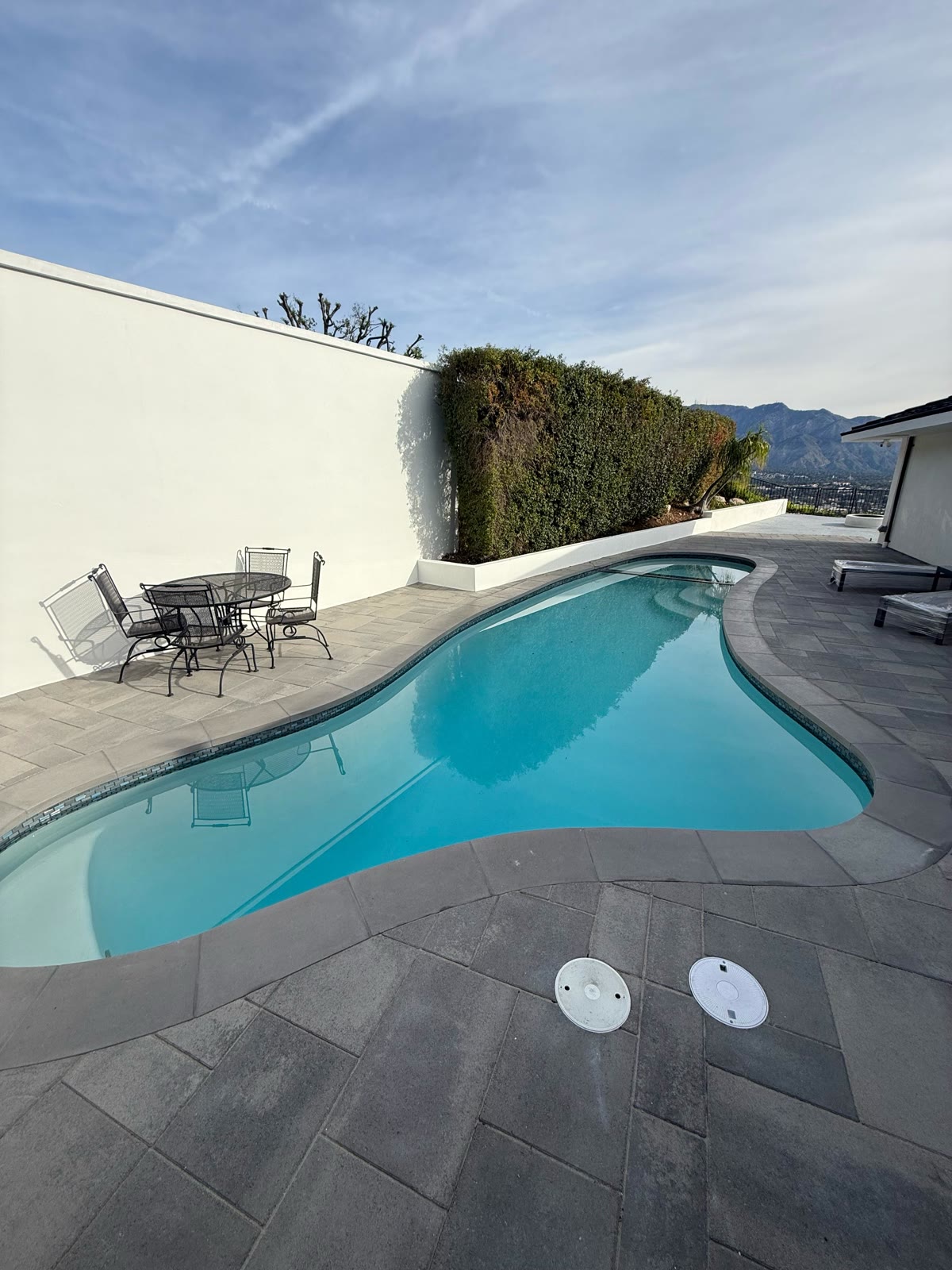 Freeform pool with hillside mountain view and patio set
