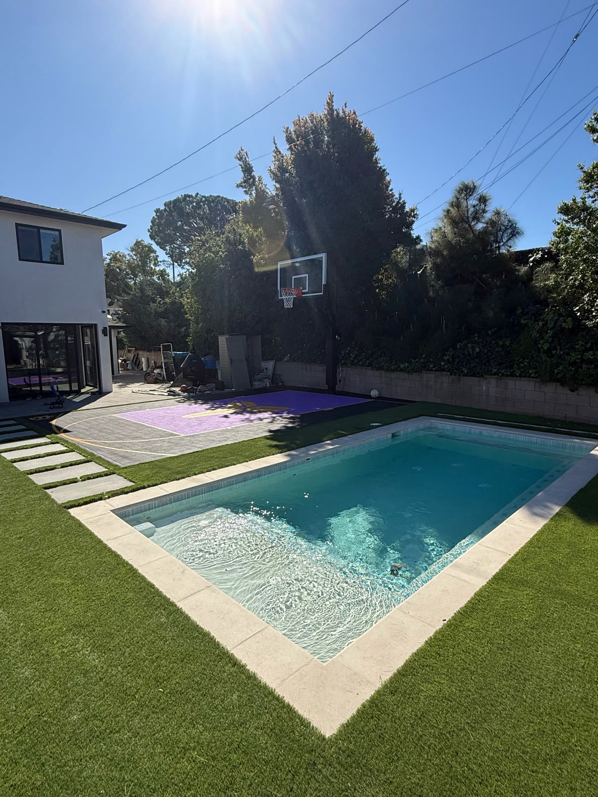 Rectangular pool with turf deck and sport court at golden hour