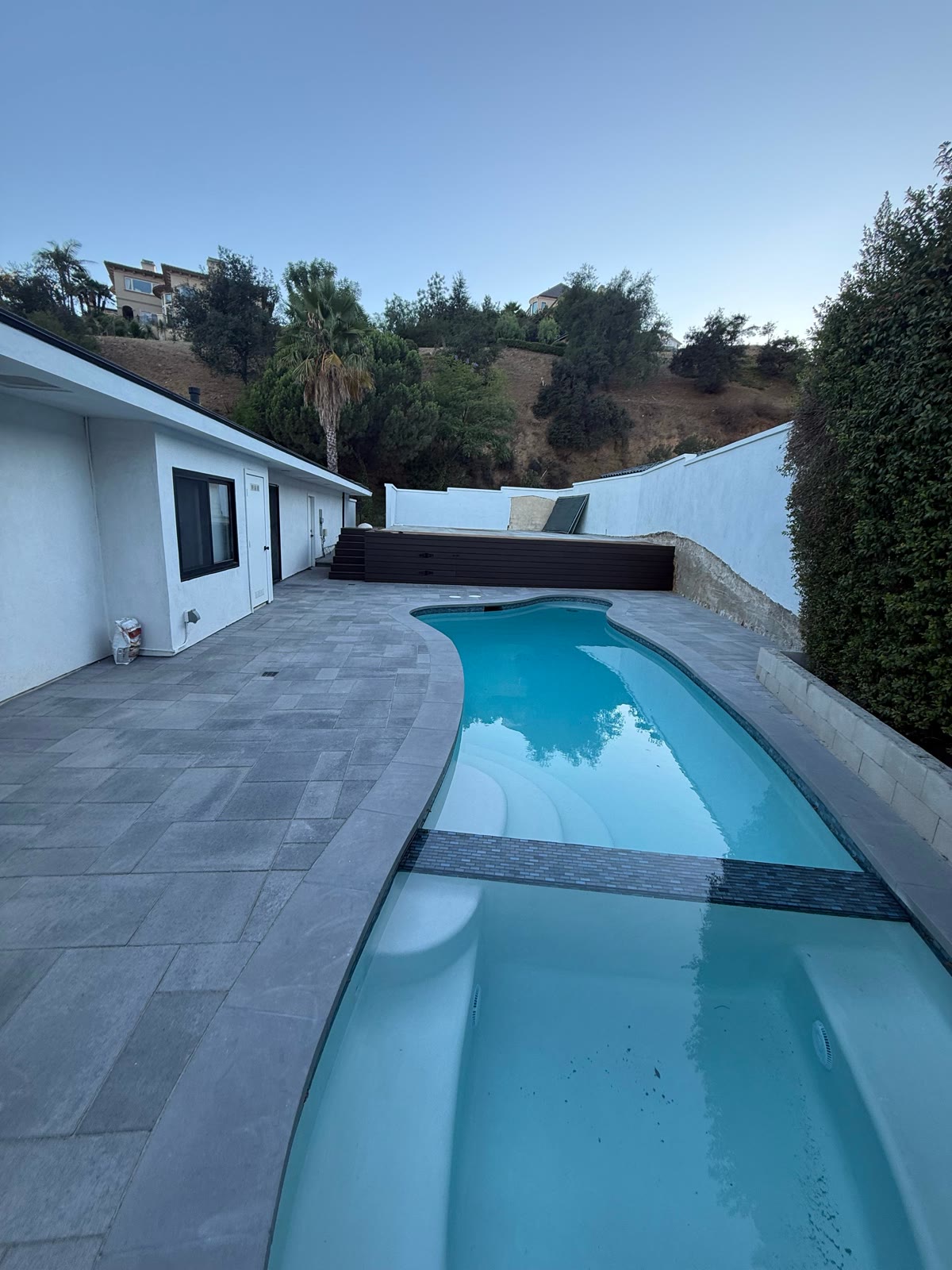 Freeform pool and spa with hillside view at dusk
