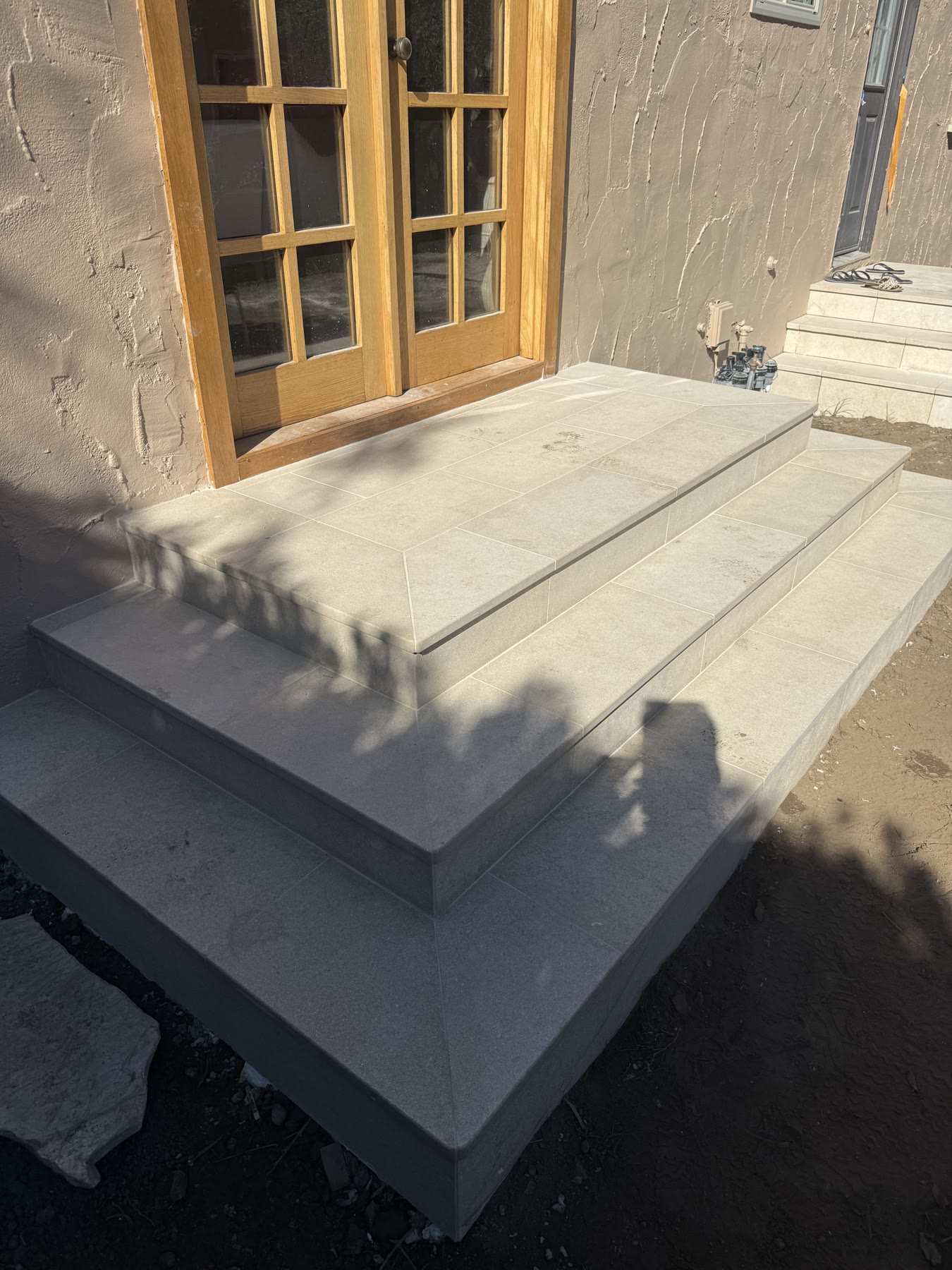 Custom travertine tile steps leading to French doors