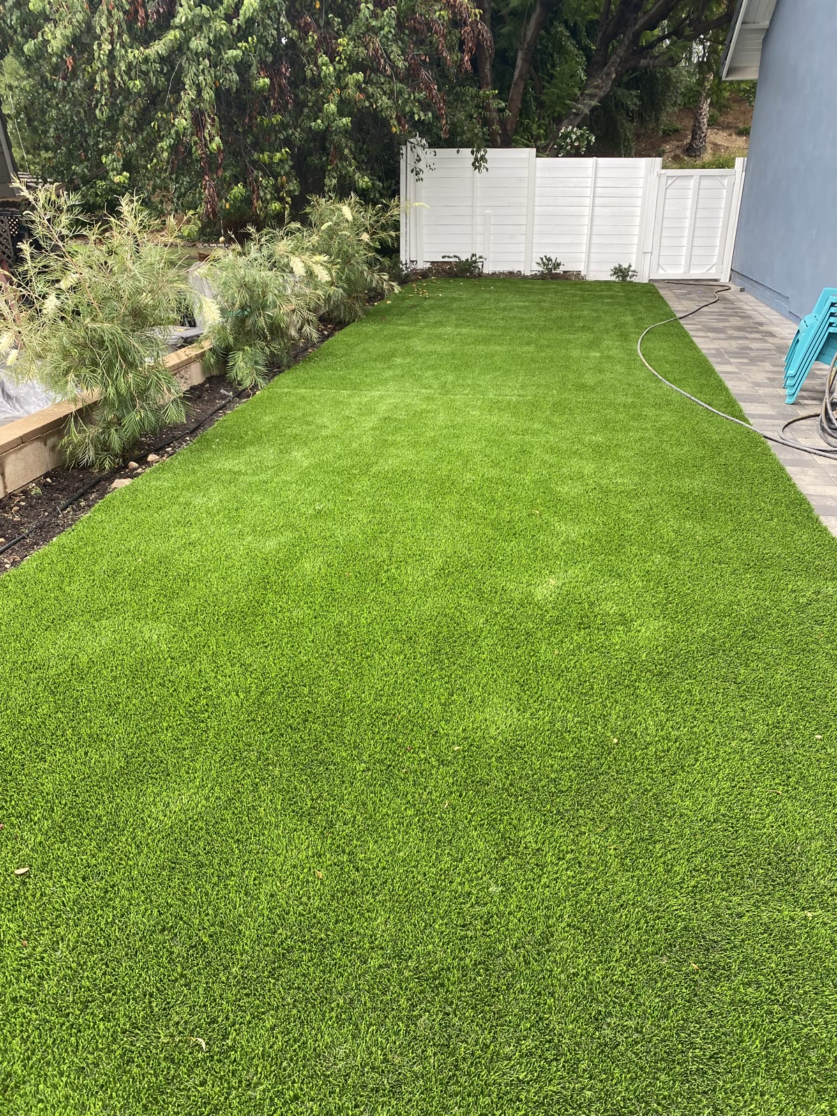 Lush turf lawn with white vinyl fence and planter