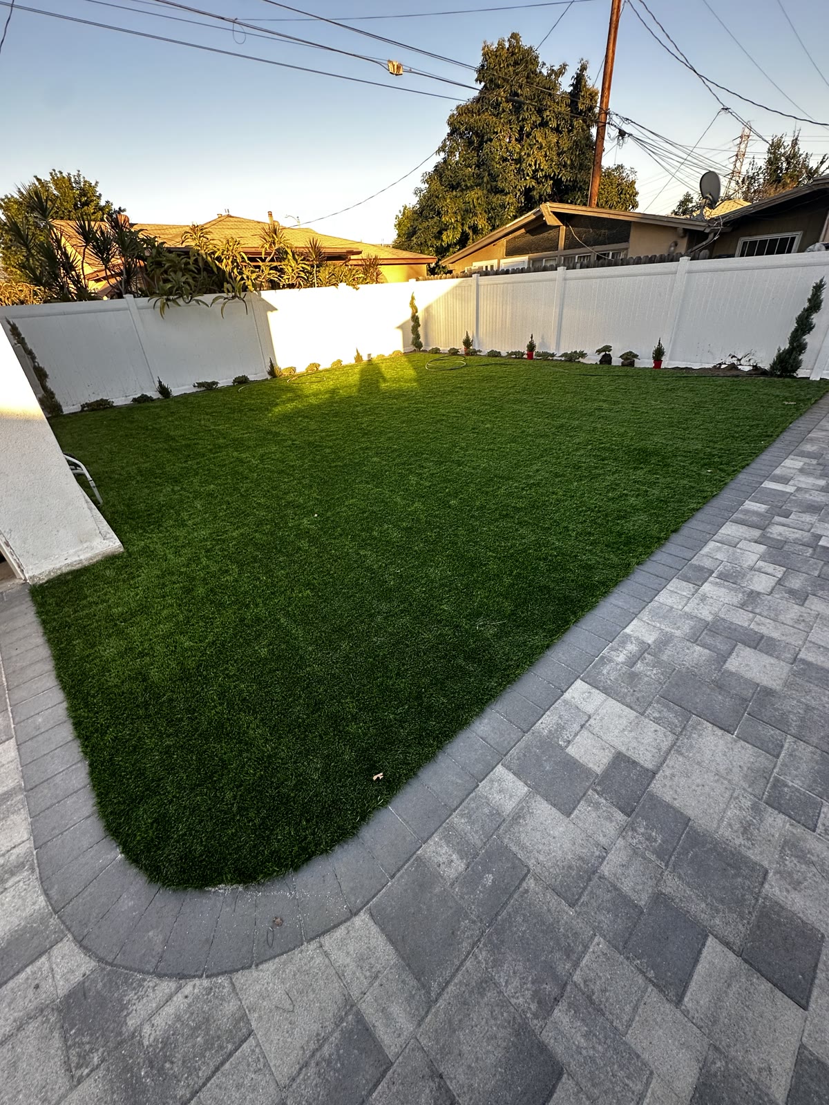 Backyard turf lawn with paver border at golden hour