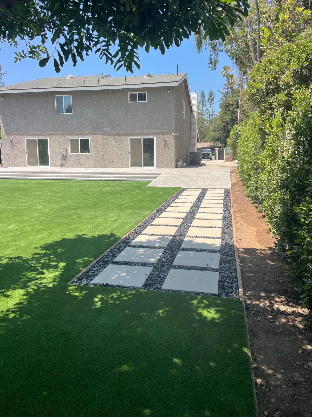Lush turf lawn with stepping-stone and gravel paver path to the house